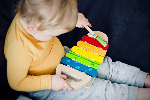 A toddler playing on a colorful xylophone