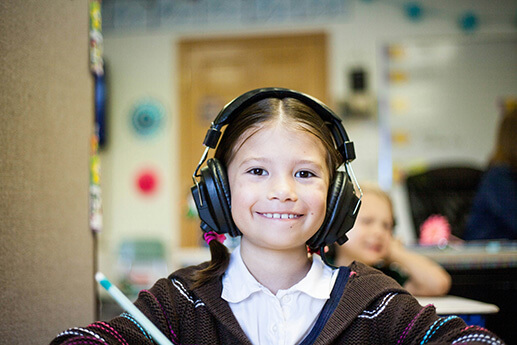 A young girl wearing headphones at her daycare center. 