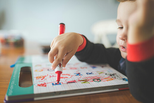 A child practicing his letters with a red marker.