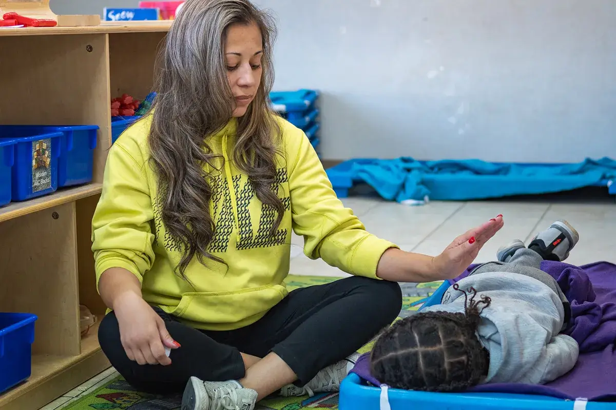Childcare provider sitting next to napping child