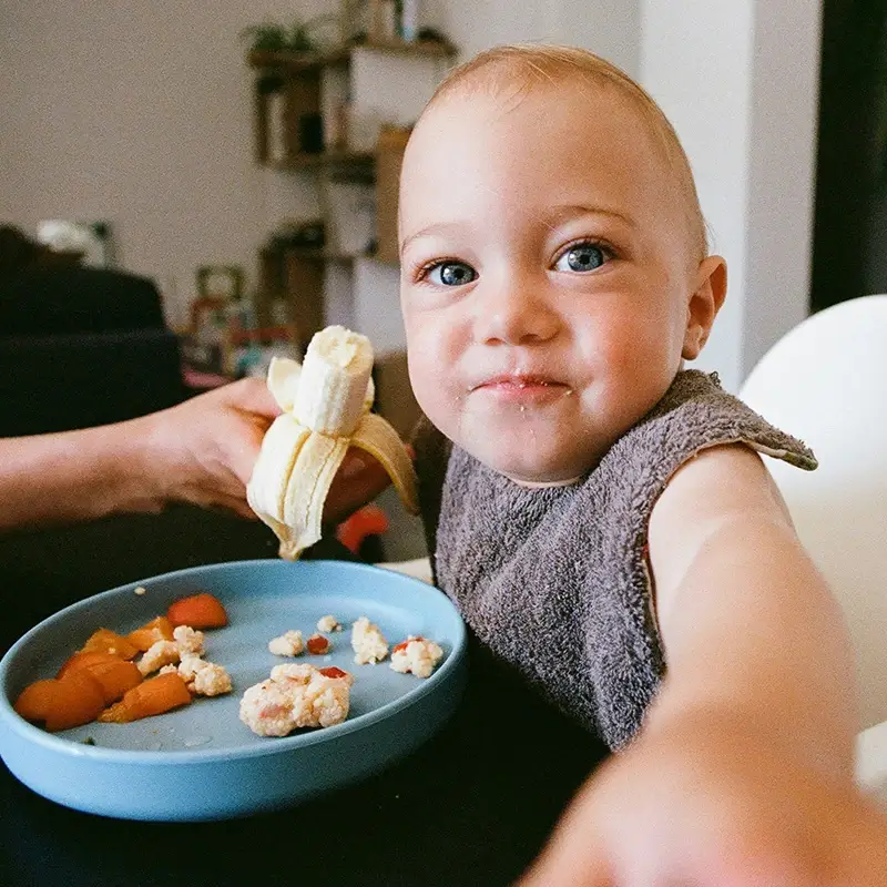 Smiling baby eating banana
