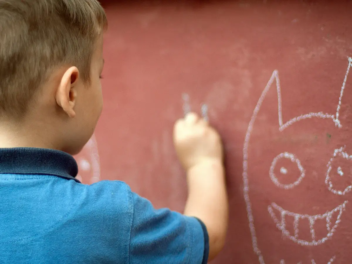 A boy drawing with chalk on a wall