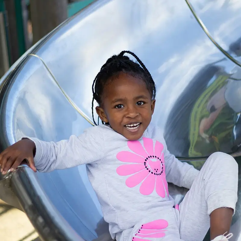 girl-on-slide A young girl sliding down a slide at daycares that accept DHS near me
