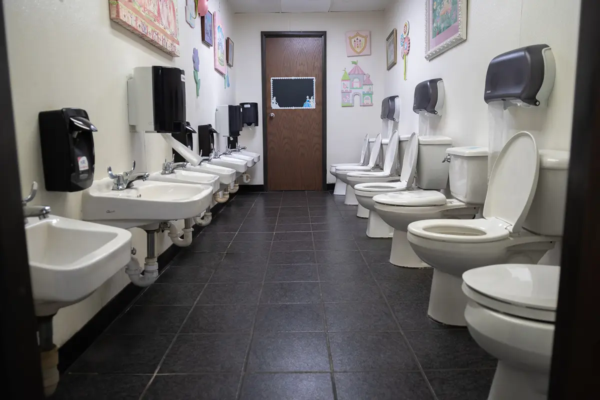 Tips for Potty Training - Child Care Inc Child-friendly daycare bathroom with small toilets and sinks for potty training.